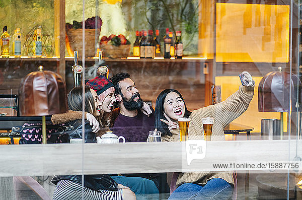 Friends meeting in a trendy bar  taking smartphone selfies