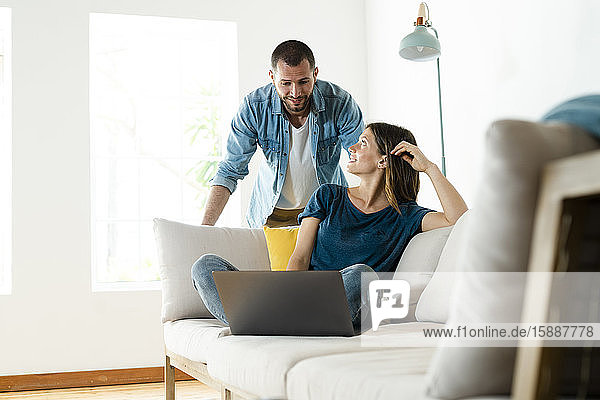 Young couple on couch at home with laptop