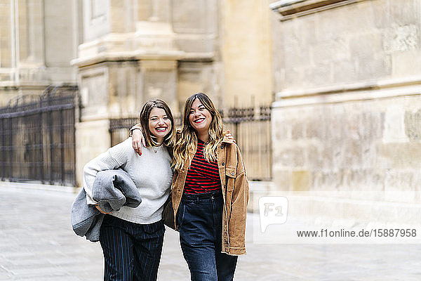 Zwei glückliche junge Frauen gehen in der Stadt spazieren