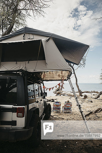 Rear view of friends relaxing by jeep at beach USA Hawaii Maui