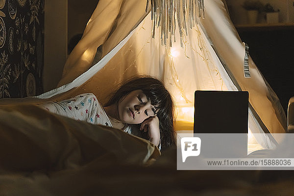 Porträt eines auf dem Bett liegenden Mädchens mit Laptop