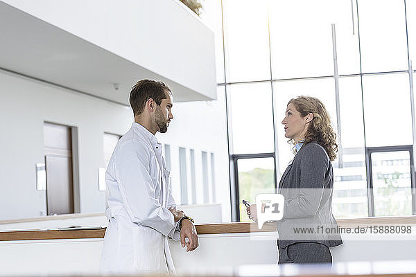 Geschäftsfrau und Arzt sprechen im Krankenhaus