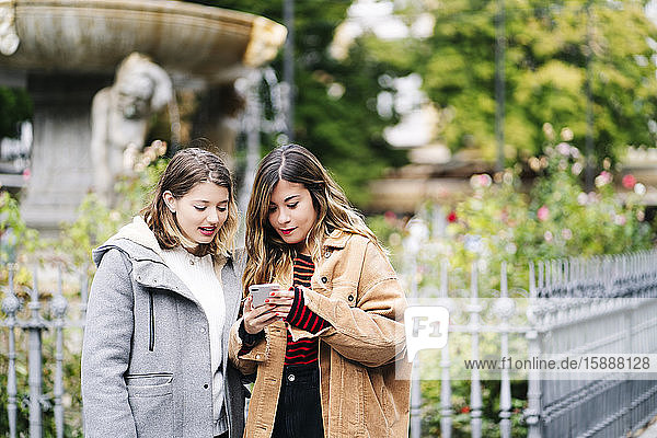 Two young women using smartphone in the city