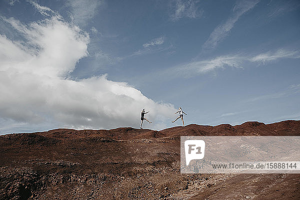 Distant view of friends practicing yoga on dramatic landscape at Waimea Canyon Kauai Hawaii USA