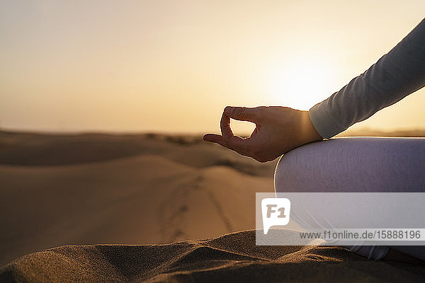 Nahaufnahme einer Frau  die bei Sonnenuntergang in Sanddünen Yoga praktiziert  Gran Canaria  Spanien