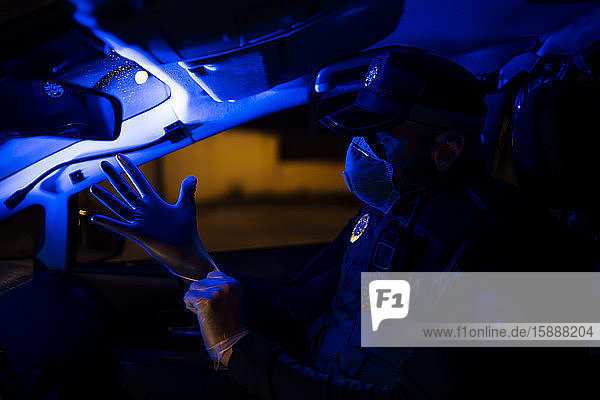 Polizist im Notfalleinsatz  zieht Schutzhandschuhe an