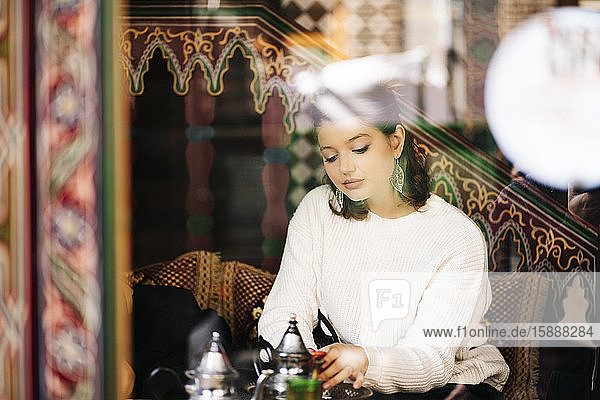 Porträt einer nachdenklichen jungen Frau beim Teetrinken in einem Teeladen