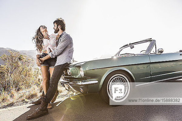 Happy couple embracing at convertible car on a country road