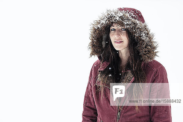 Portrait of young woman wearing hooded jacket in winter