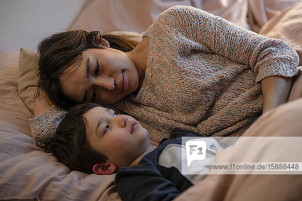 Porträt einer Mutter  die mit ihrem kleinen Sohn auf dem Bett liegt und sich entspannt