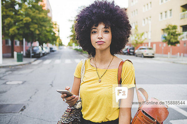 Porträt einer selbstbewussten jungen Frau mit Afrofrisur in der Stadt