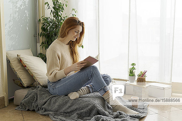 Junge Frau liest zu Hause ein Notizbuch