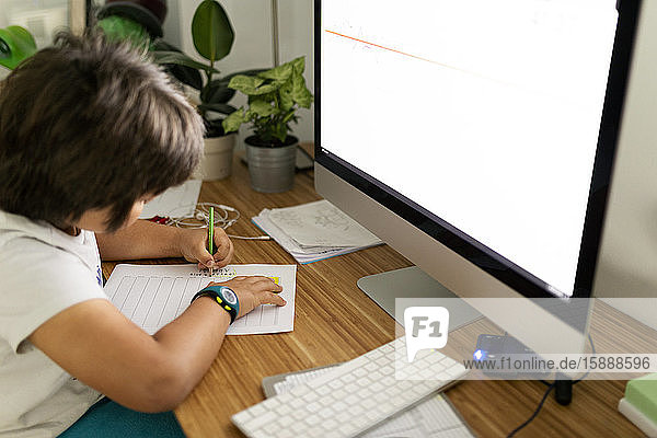 Junge sitzt zu Hause am Schreibtisch und malt Zeitplan