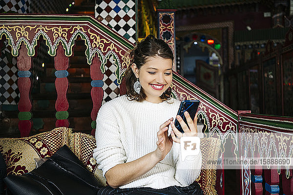 Porträt einer glücklichen jungen Frau in einem Teegeschäft mit einem Smartphone