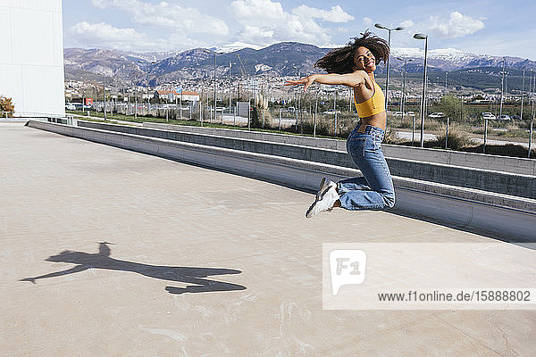 Porträt einer glücklichen jungen Frau  die in die Luft springt