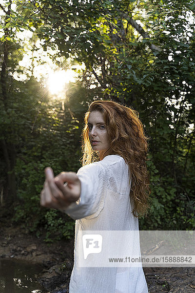 Junge rothaarige Frau streckt im Wald ihre Hände aus