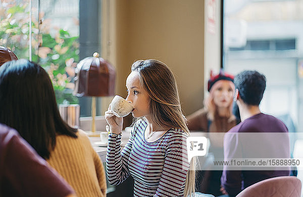 Young woman sitting in busy bar of a restaurant  drinking coffee