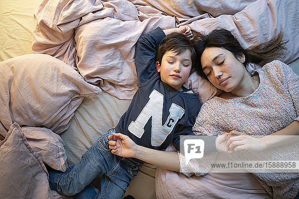 Mother and little son relaxing together on bed