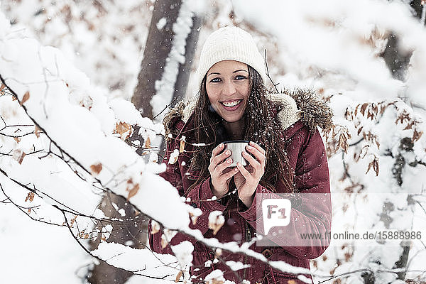 Porträt einer glücklichen jungen Frau mit Heißgetränk im Winter