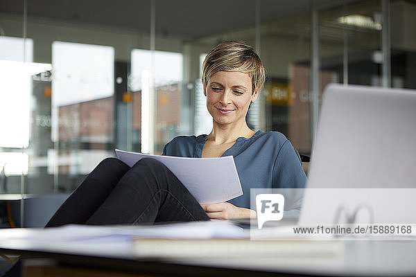 Lächelnde Geschäftsfrau arbeitet am Schreibtisch im Büro