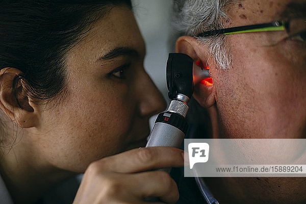 ENT physician examining ear of a senior man with an otoscope