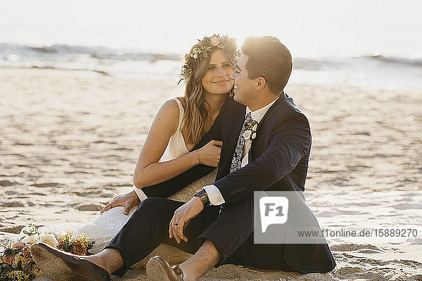 Glückliches Brautpaar sitzt am Strand