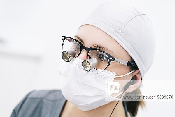 Portrait eines Zahnarztes mit Lupe und Maske