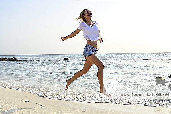 Beautiful woman running and jumping for joy on the beach