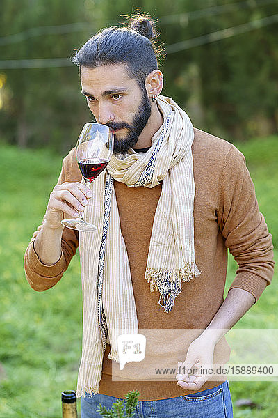 Porträt eines jungen Mannes bei einer Rotweinverkostung auf dem Land