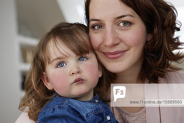 Portrait of happy young mother head to head with her little daughter