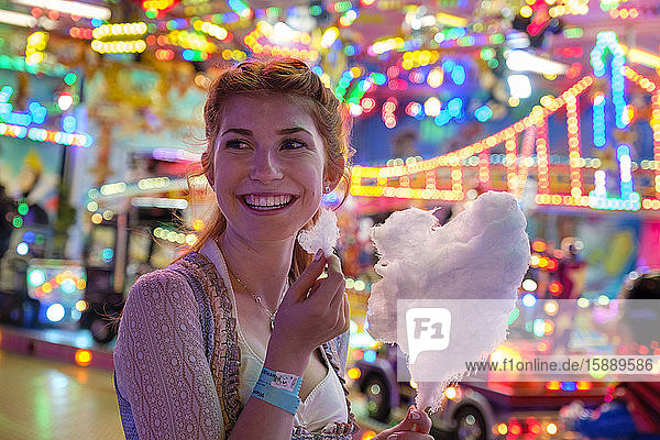 Porträt eines glücklichen rothaarigen Teenagers mit Zuckerwatte auf dem Oktoberfest