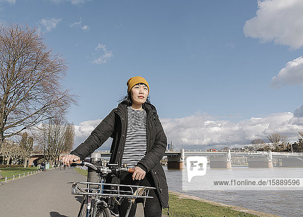 Woman with bicycle on the riverbank  Frankfurt  Germany