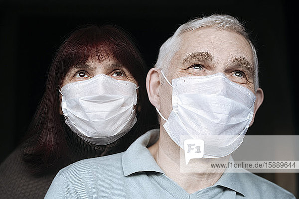 Porträt eines älteren Ehepaares  das zu Hause Masken trägt