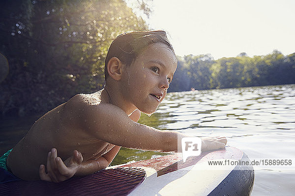 Nasser Junge klettert in der Abenddämmerung auf SUP-Brett