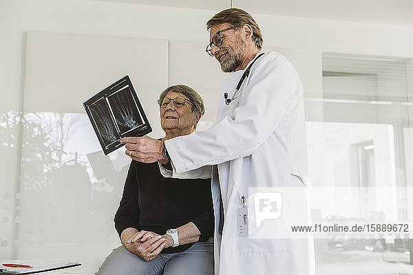 Doctor discussing x-ray image of broken hand with senior patient