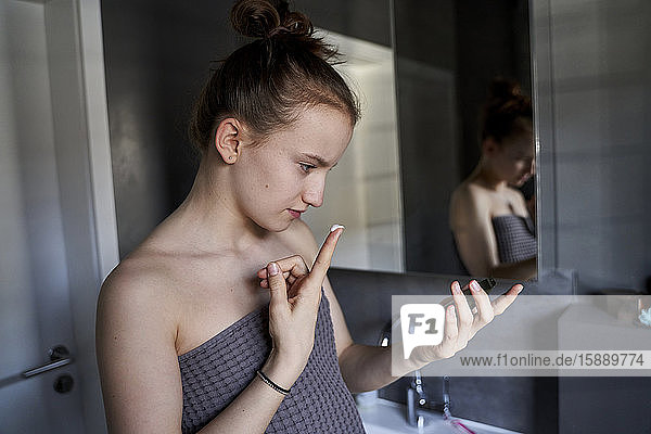 Girl using face cream in bathroom
