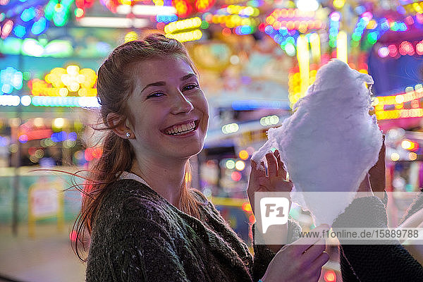Portrait of happy redheaded teenage girl with candy floss at Oktoberfest