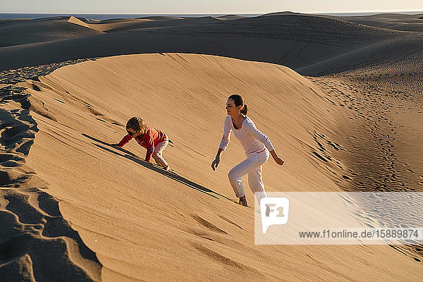 Mutter und Tochter klettern auf eine Sanddüne  Gran Canaria  Spanien