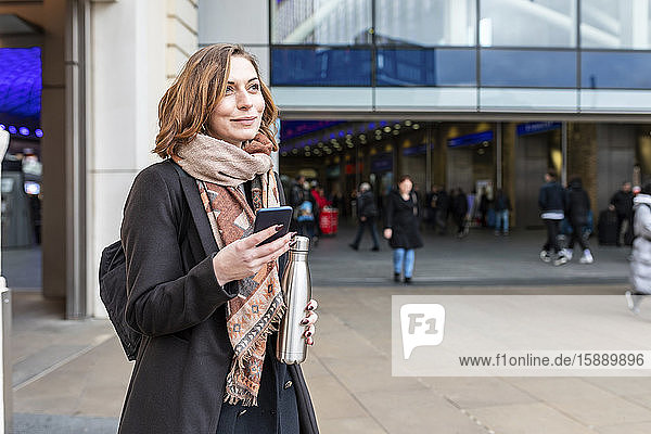 Porträt einer Frau mit Mobiltelefon vor dem Bahnhof  London  UK