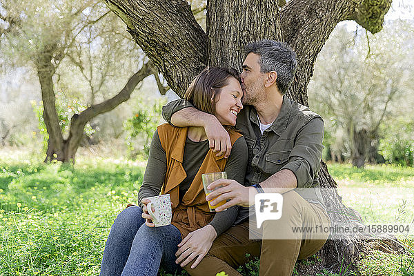 Happy couple sitting at a tree in the countryside