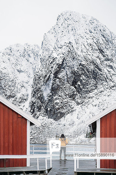 Tourist standing at a hut at the coast  Lofoten  Norway