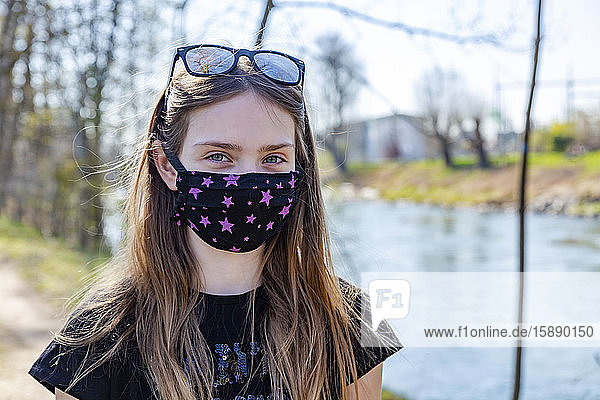 Mädchen mit selbstgemachter Schutzmaske am Flussufer