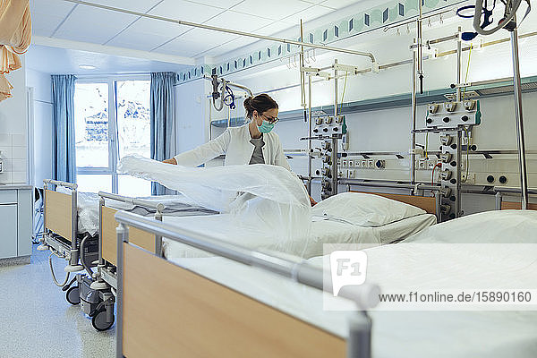 Doctor preparing bed in hospital room