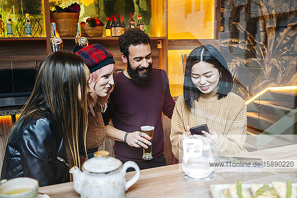 Freunde treffen sich in einer angesagten Bar mit Blick auf das Smartphone