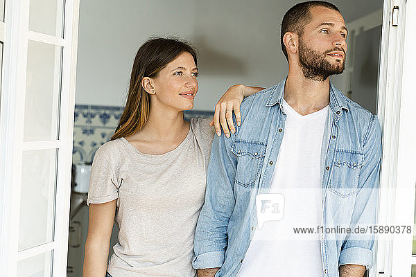 Attraktives junges Paar  das zu Hause gemeinsam in der Tür steht und nach draußen schaut