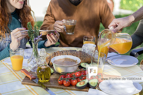 Nahaufnahme von Freunden  die ein gesundes veganes Frühstück im Freien genießen