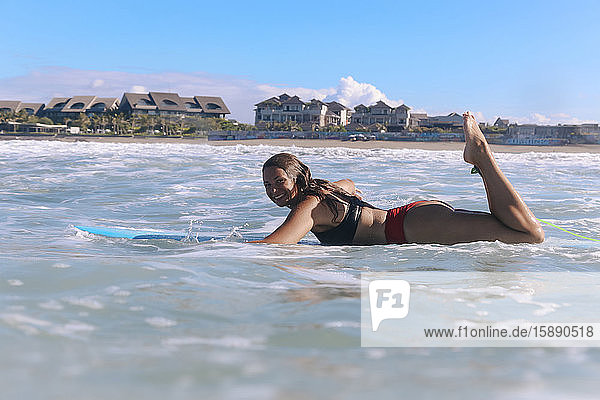 Auf einem Surfbrett liegender weiblicher Surfer  Bali  Indonesien