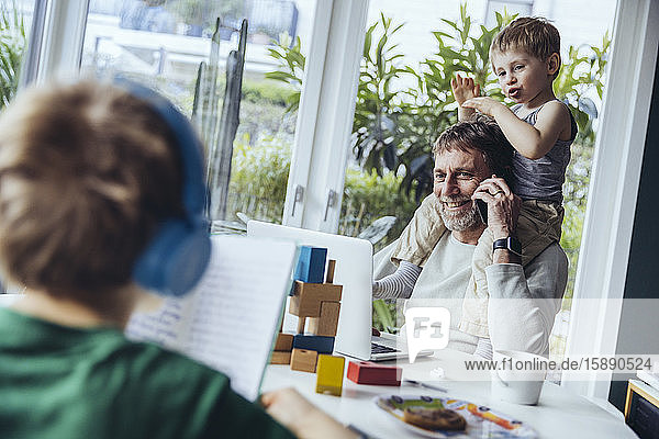 Vater arbeitet von zu Hause aus  telefoniert  während die Kinder spielen