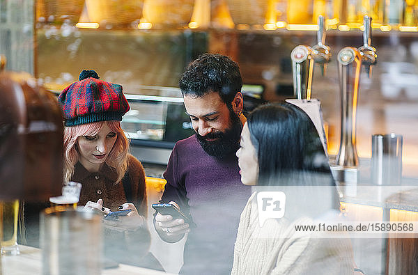 Freunde treffen sich im Restaurant  unterhalten sich  schauen auf Smartphones