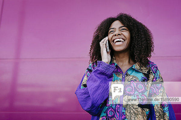 Lächelnde Frau beim Telefonieren  rosa Wand im Hintergrund